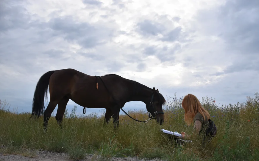 Frau mit Buch und Pferd auf Wiese