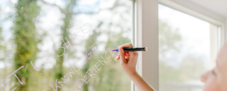 Frau schreibt einen Schriftzug am Fenster
