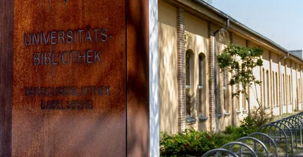 Flat, elongated building, on the left in the foreground a metal column with the lettering "Universitätsbibliothek Bereichsbibliothek Babelsberg".