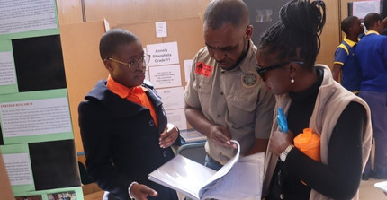 Learner discussing with educators in front of poster