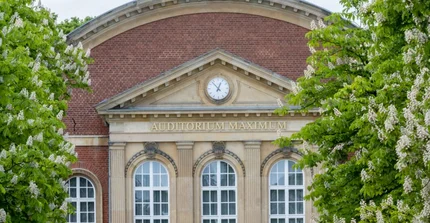 Facade of the Audimax of the University of Potsdam, lined on the left and right by flowering chestnut trees