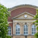 Facade of the Audimax of the University of Potsdam, lined on the left and right by flowering chestnut trees