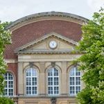 Facade of the Audimax of the University of Potsdam, lined on the left and right by flowering chestnut trees