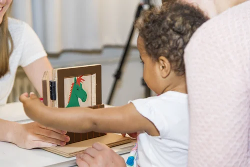 Kind sitzt auf Mamas Schoß und spielt mit Spielzeug