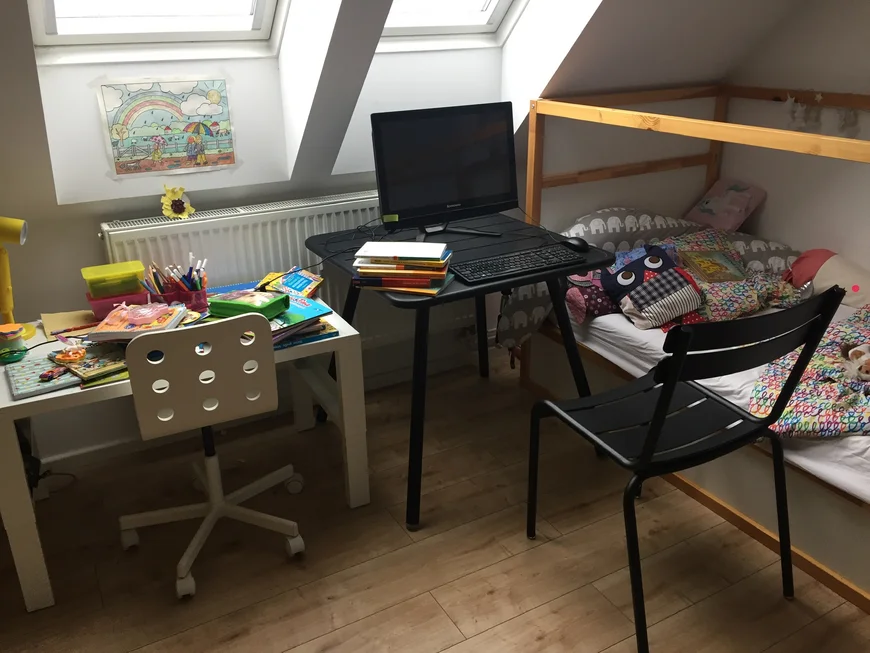 Ein verkramter Kinderschreibtisch, rechts daneben ein Arbeitsplatz mit Laptop und daneben ein Kinderhochbett