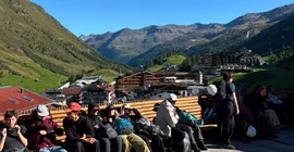 Eine gruppe von Menschen in alpiner Region. Alle rasten und wirken erschöpft, aber glücklich.