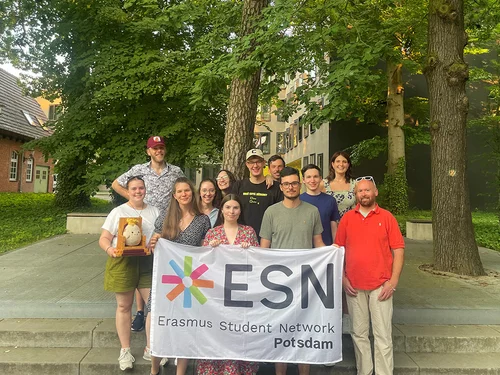 Mehrere Personen stehen auf einer Treppe mit einer Flagge mit ESN Logo