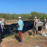 Eine Gruppe Menschen beim Abdecken des Grabungsareals.