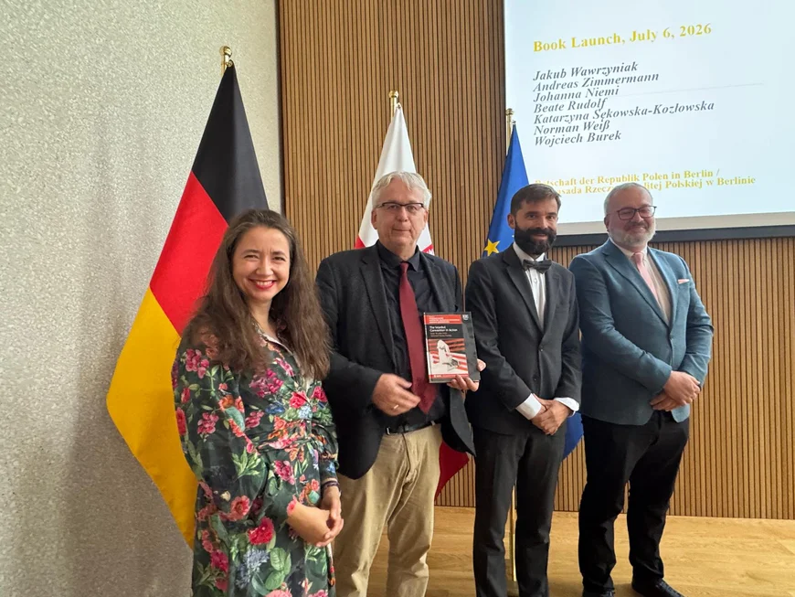 Die Heausgeber und der polnische Geschäftsträger stehen vor der deutschen und der polnischen Fahne und präsentieren den vorgestellten Band.