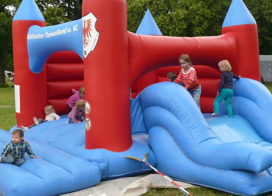 Mehrere Kinder spielen auf einer großen Hüpfburg.