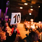 Blick ins Publikum beim Science Slam. Eine "10" wird im Vordergrund hochgehalten.