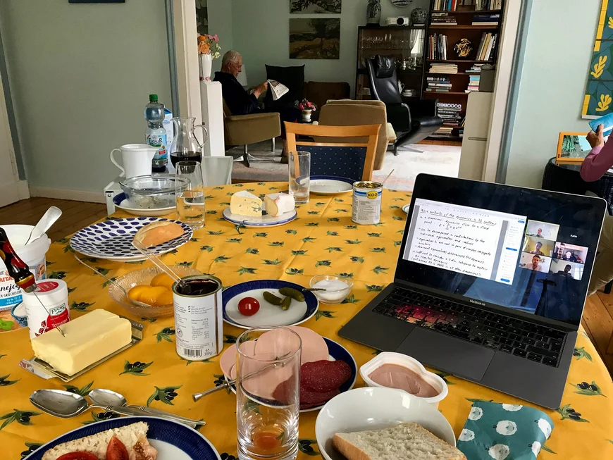 Tisch mit Frühstück, Laptop und Opa im Hintergrund