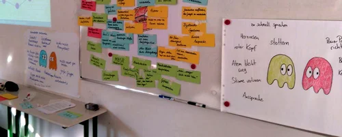 Tafel mit Flipchartbogen und Karteikarten, im Hintergrund Beamer-Projektion, zum Thema Vortragen
