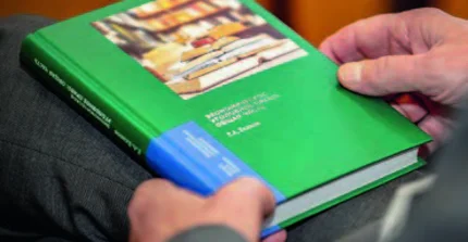 Ein Lehrbuch zum russischen Wirtschaftsstrafrecht liegt auf dem Schoß
