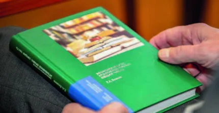 Ein Lehrbuch zum russischen Wirtschaftsstrafrecht liegt auf dem Schoß