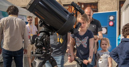 Auf dem Foto sind mehrere Teilnehmer der PTDW zu sehen. Das Mädchen im Vordergrund schaut durch ein Fernglas, hinter ihr stehen ihr Vater und ihre Schwester. Das Foto wurde von Thomas Roese aufgenommen.
