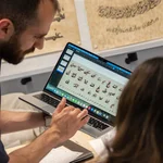 Mann mit Laptop, auf dem arabische Schriftzeichen zu sehen sind