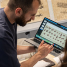 Mann mit Laptop, auf dem arabische Schriftzeichen zu sehen sind