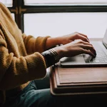 Schreiber:in sitzend am Laptop