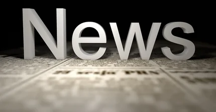 Button zur Unterseite Aktuelles: Im Bild ist das Wort "News" prominent in hellen, schattierten 3D-Buchstaben dargestellt, die auf einer angedeuteten Zeitungsoberfläche platziert sind.