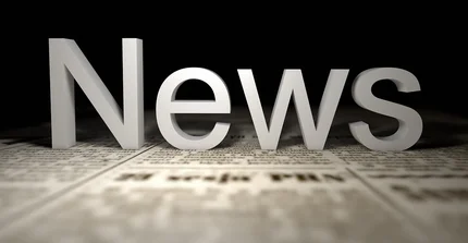 Button zur Unterseite Aktuelles: Im Bild ist das Wort "News" prominent in hellen, schattierten 3D-Buchstaben dargestellt, die auf einer angedeuteten Zeitungsoberfläche platziert sind.