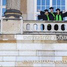 Finales Foto: Zwei Absolventinnen und ein Absolvent krönen ihren Abschluss mit einem Erinnerungsbild auf dem Balkon des Südcommuns.
