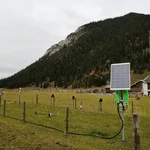 Field site Esterberg: A bright green CRNS sensor with solar panel standing on a green pasture with forested hills in the background | Photo: Cosmic Sense Consortium