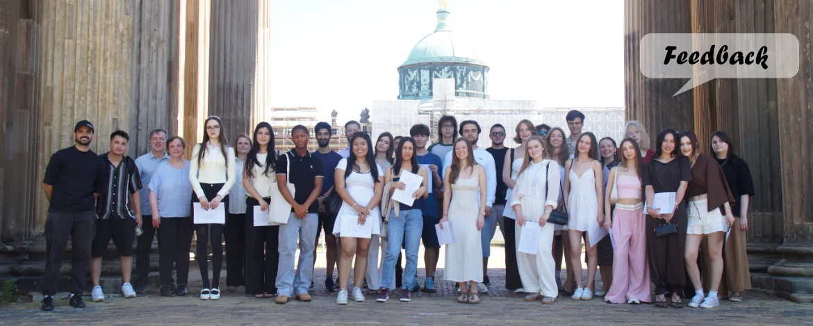 Gruppe vor den Kollonanden mit Sprechblase, in der "Feedback" steht - 