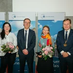 Vier Personen - zwei Frauen und zwei Männer - auf einem Podium