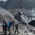 Menschen stehen vor einer torartigen Formation in einem Gletscher