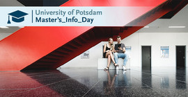 Two people sitting under a red staircase.