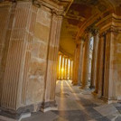Blick aus einem halbrunden Säulengang auf ein historisches Nebengebäude des Neuen Palais