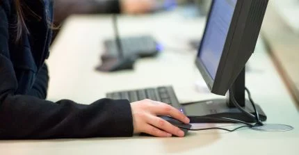 Hand an Maus vor Computerbildschirm