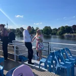 Auf dem Bild sieht man die Bootstour auf dem Griebnitzsee während der 30-Jahr-Feier des Studiengangs. Die Sonne lacht, und die Teilnehmenden genießen die Fahrt in ausgelassener Stimmung.