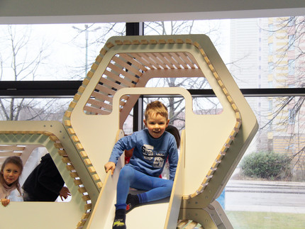 Kinder spielen auf einem Indoor-Spielplatz. Ein Junge sitzt auf der Rutsche.