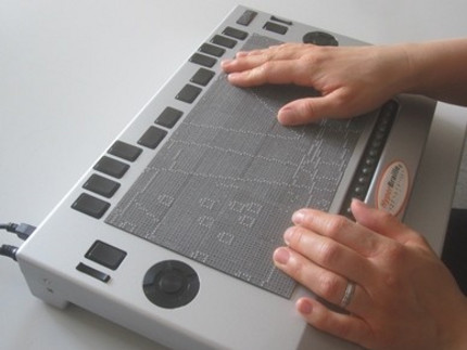 Foto des taktilen Flächendisplays BrailleDis mit Händen, welche die Darstellung eines taktilen Stadtplans erkunden