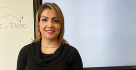 Entisar Karkoli in front of a blackboard.