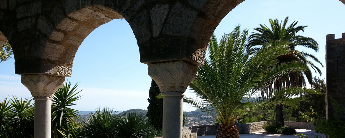Blick auf einen mediterranen Garten mit Palme und Meerblick in Hyères-les-Palmiers (Côte d'Azur)