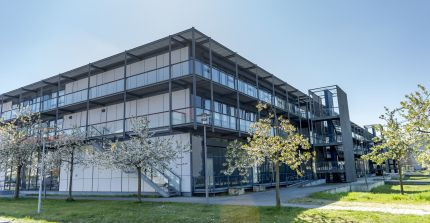 Fassade aus Stahl und Glas eines Forschungsgebäudes, davor Bäume