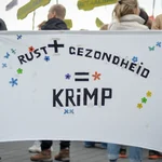 Protesters carrying a banner with the phrase 'peace' plus 'health' equals 'shrink'