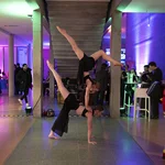 Zwei Akrobatinnen in einem Foyer mit bunten Lichtern.