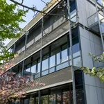 Fassade aus Stahl und Glas eines Forschungsgebäudes, davor zwei Bäume
