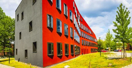 Ein rotes Gebäude, das eine wellenförmig geschwungene Fassade hat
