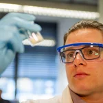 This image shows a chemist in a laboratory who is looking at a sample.