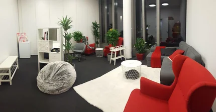 The picture shows a cozy sitting area with two red armchairs and some indoor plants.