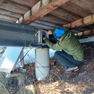 Field site Leutasch: Scientist kneeling below the patio of an alpine hut, installing electronnics for measuing equipment | Photo: Cosmic Sense Consortium