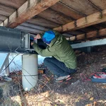 Field site Leutasch: Scientist kneeling below the patio of an alpine hut, installing electronnics for measuing equipment | Photo: Cosmic Sense Consortium