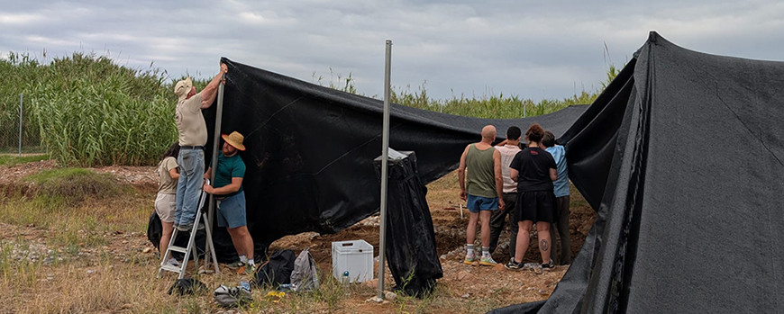 Teilnehmende der Summer School bauen schwarze zeltartige Sonnenschutzplanen ab.
