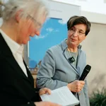 Zwei Frauen auf einem Podium, eine hält ein Mikrofon in der Hand