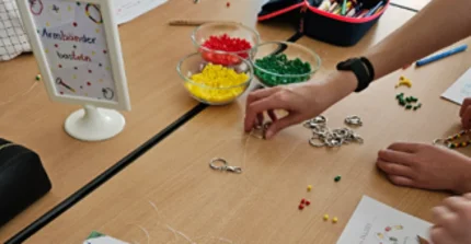 Das Bild zeigt mathematikdidaktische Materialien auf einem Tisch und die Hände von Kindern, die mit den Materialien arbeiten.